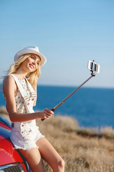 Woman making selfie portrait near the car by the sea. — Zdjęcie stockowe