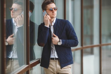 Genç işadamı cep telefonu açık havada üzerinde konuşuyor.