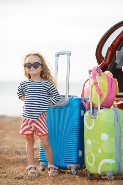 A little girl goes on a journey on a red car — Stock Photo, Image