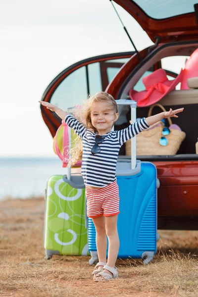 Mała dziewczynka jedzie w podróż na czerwonym samochodzie — Zdjęcie stockowe