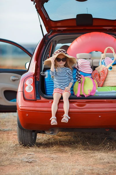 Little girl in straw hat sitting in the trunk of a car — Stock Photo, Image