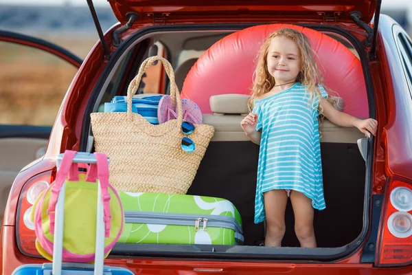 Portrait of a little girl sitting in the trunk of a car — Stock Photo, Image