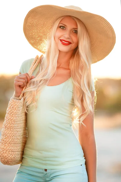 Heldere blonde in mooie hoed in de stralen van de ondergaande zon — Stockfoto