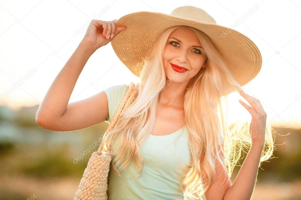 Bright blonde in beautiful hat in the rays of the setting sun