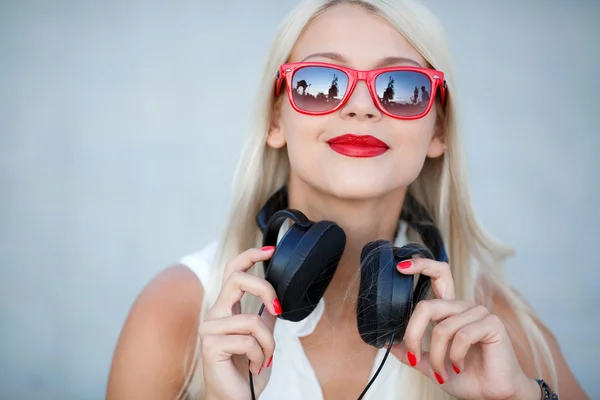 Chica rubia sonriente en auriculares sobre fondo azul — Foto de Stock