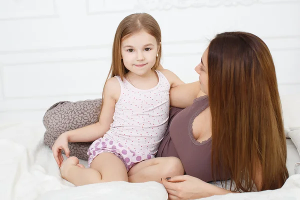 Mother and daughter lying on a white bed in the bedroom — Φωτογραφία Αρχείου