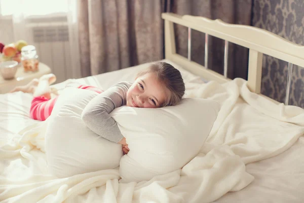一个小女孩醒来，拥抱枕头的早晨肖像 — 图库照片