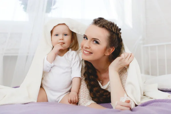 Familia feliz, madre jugando con su bebé en el dormitorio . — Foto de Stock