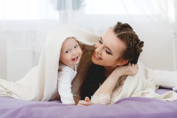 Familia feliz, madre jugando con su bebé en el dormitorio . — Foto de Stock