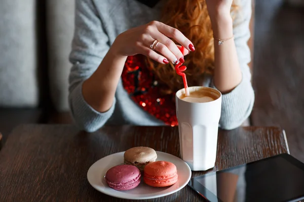 En rödhårig kvinna med en kopp kaffe i caféet — Stockfoto