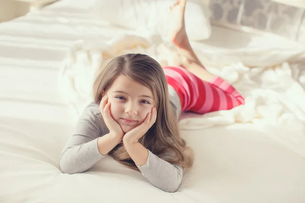 Portrait of a cute little girl, waking up and lying in bed in the morning — Stok fotoğraf