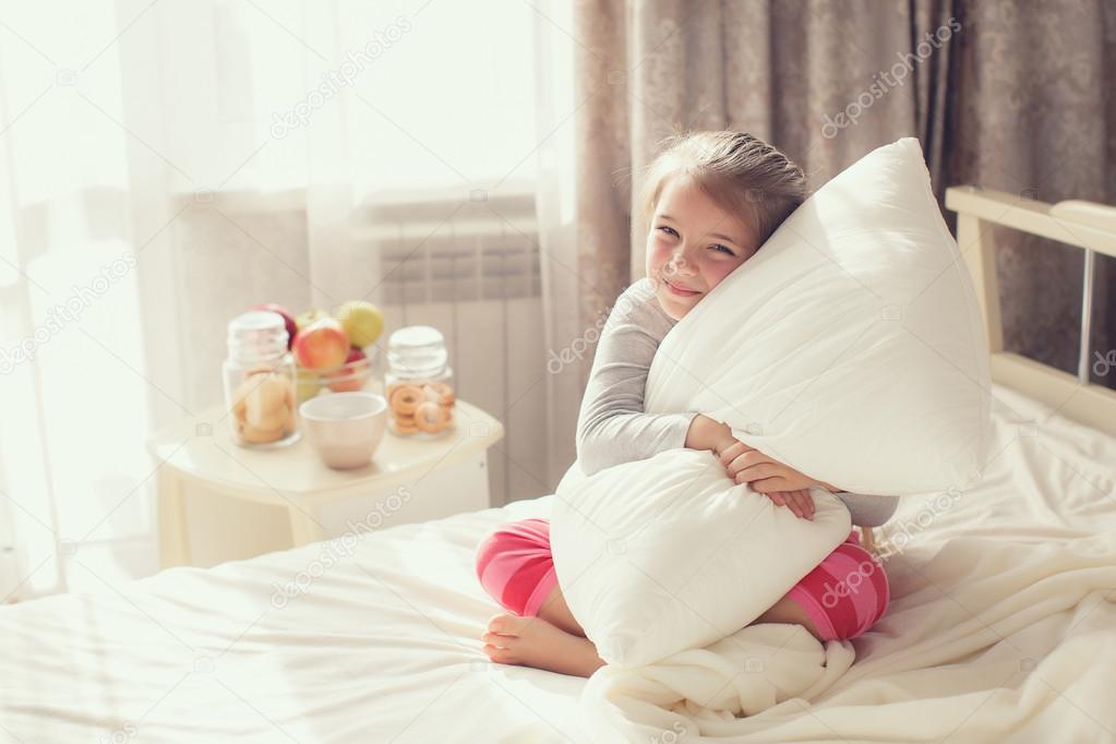 Morning portrait of a little girl waking up,embracing the pillow