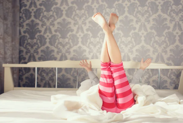 Criança fazendo exercícios enquanto estava deitada na cama — Fotografia de Stock