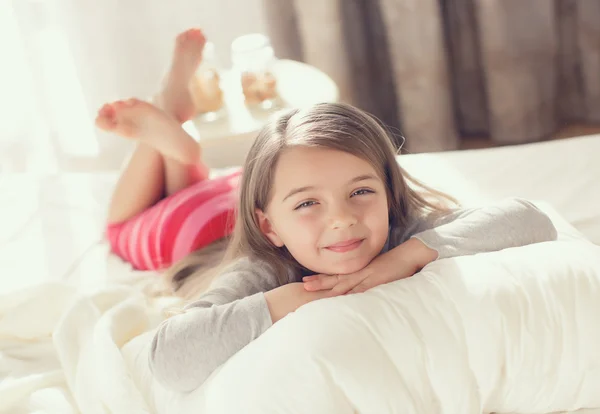 รูปภาพของเด็กผู้หญิงที่น่ารัก ตื่นขึ้นมาและนอนบนเตียงในตอนเช้า — ภาพถ่ายสต็อก