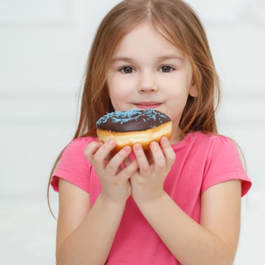 Adorable little girl with a chocolate donut