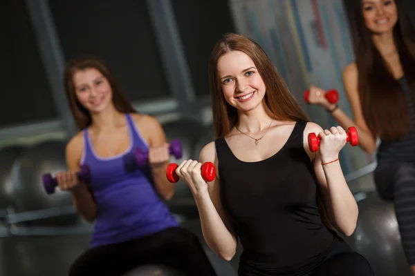 Deportivas en el gimnasio haciendo ejercicio con pesas —  Fotos de Stock