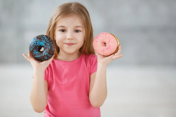 Menina adorável com um donut de chocolate — Fotografia de Stock
