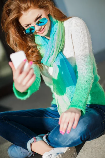 Girl makes a selfie sitting on the street in the city — Stock Photo, Image