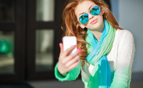 Girl makes a selfie sitting on the street in the city — Stock Photo, Image