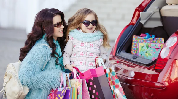 Uma mulher com uma criança depois de fazer compras carregar o carro — Fotografia de Stock