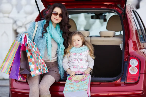 A woman with a child after shopping load the car — Stock Photo, Image