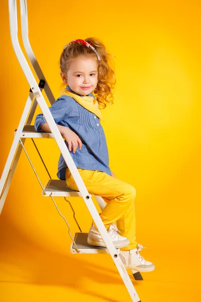 Grappig klein meisje op een heldere gele achtergrond. — Stockfoto