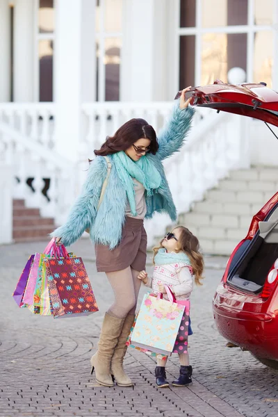 Uma mulher com uma criança depois de fazer compras carregar o carro — Fotografia de Stock