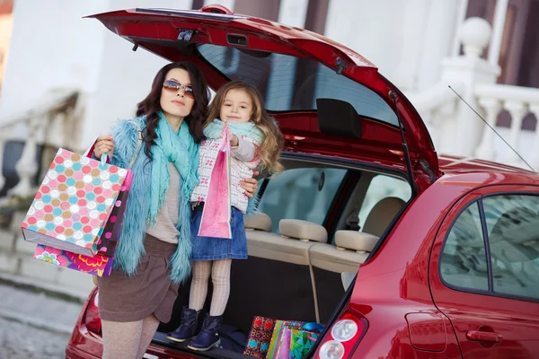 Uma mulher com uma criança depois de fazer compras carregar o carro — Fotografia de Stock