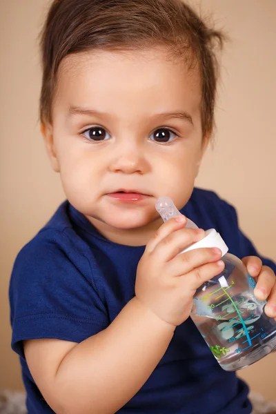 Doce bebê segurando garrafa e água potável — Fotografia de Stock