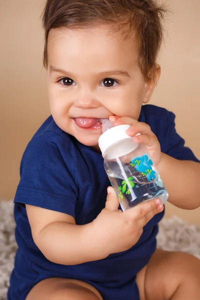 Sweet baby holding bottle and drinking water — Stock Photo, Image