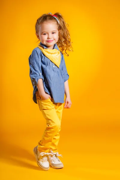 Lustige kleine Mädchen auf leuchtend gelbem Hintergrund. — Stockfoto