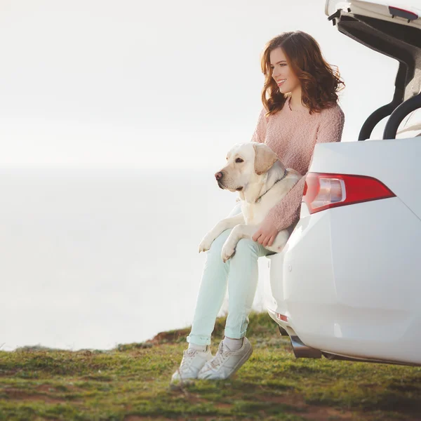 Дівчина на пляжі з білим лабрадором і білою машиною — стокове фото