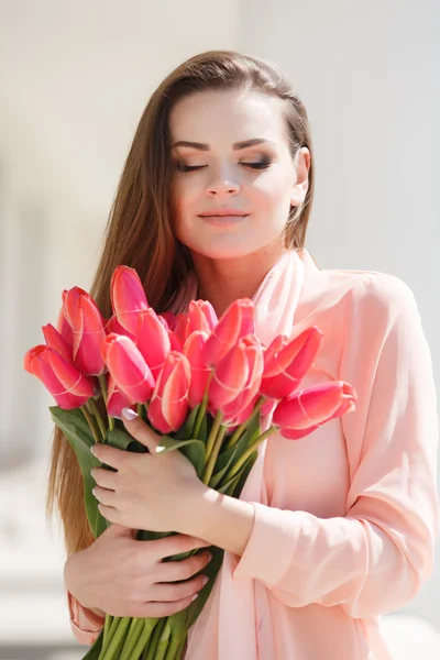 Schöne Frau mit einem Strauß roter Tulpen — Stockfoto