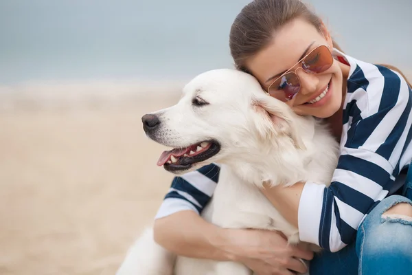 Jeune femme avec un chien sur une plage déserte — Photo