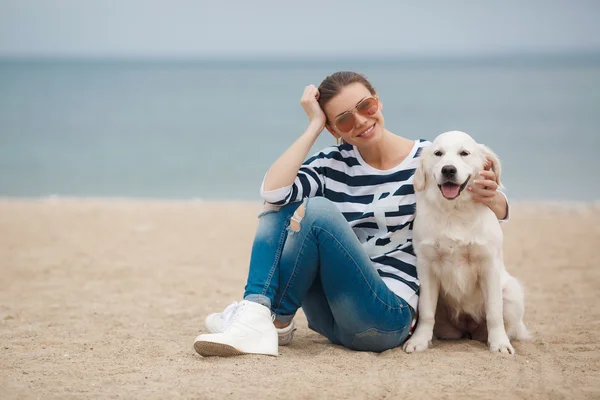 Jovem com um cachorro em uma praia deserta — Fotografia de Stock