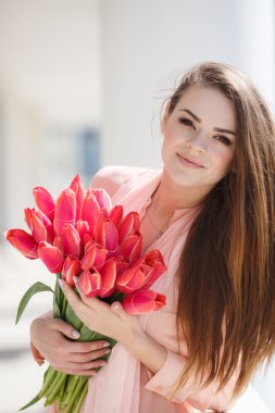 Beautiful woman with a bouquet of red tulips