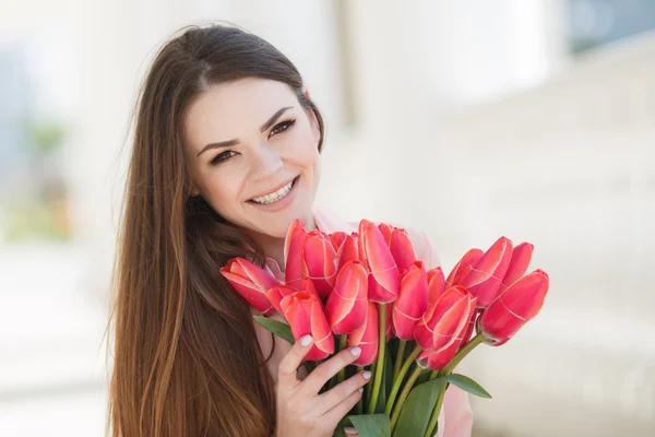 Beautiful woman with a bouquet of red tulips — Stok fotoğraf