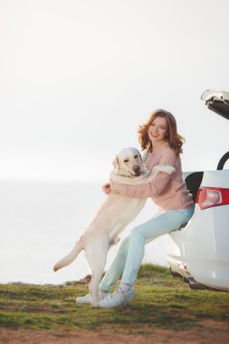 Kız beyaz bir labrador ve beyaz araba ile sahilde