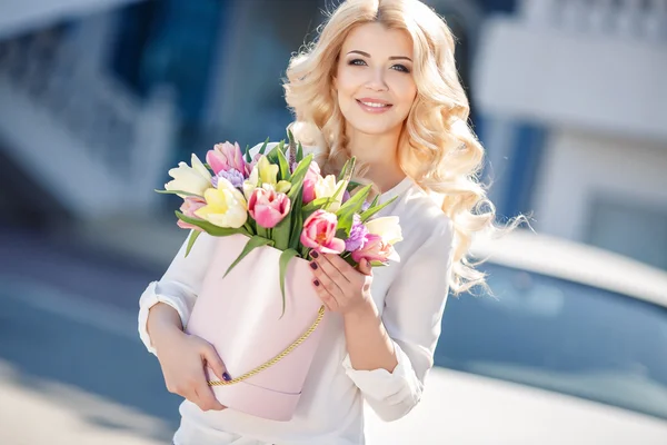 Vacker blondin med blommor i presentförpackning — Stockfoto