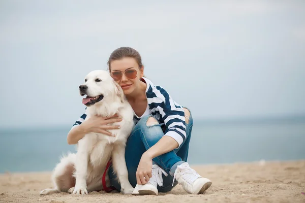 Jeune femme avec un chien sur une plage déserte — Photo