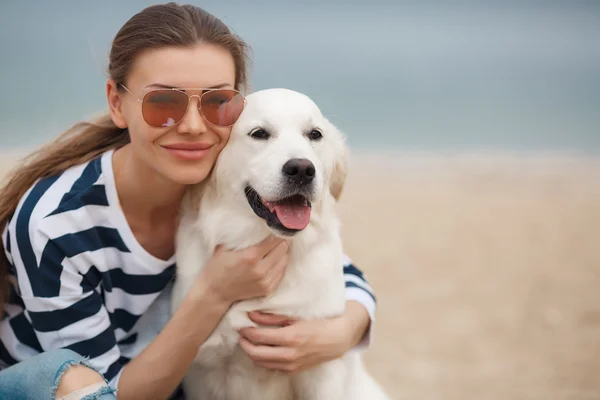 Junge Frau mit Hund an einem einsamen Strand — Stockfoto