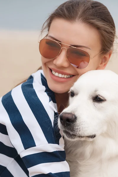 Jovem com um cachorro em uma praia deserta — Fotografia de Stock