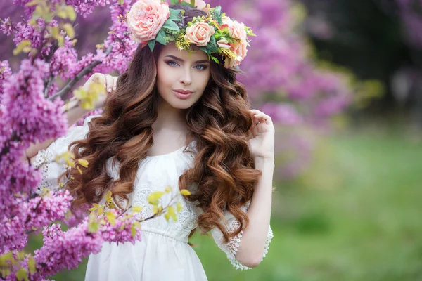 Våren porträtt av en vacker kvinna i en krans av blommor — Stockfoto