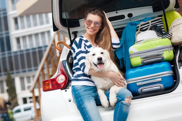 Woman with dog by car full of suitcases. — Zdjęcie stockowe