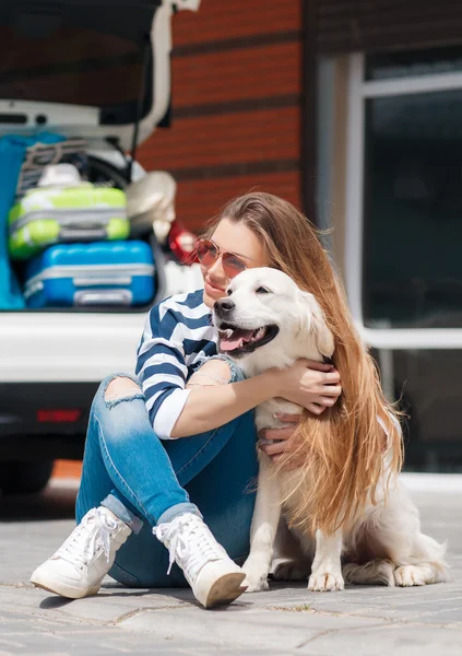 Woman with dog by car full of suitcases. — Stockfoto