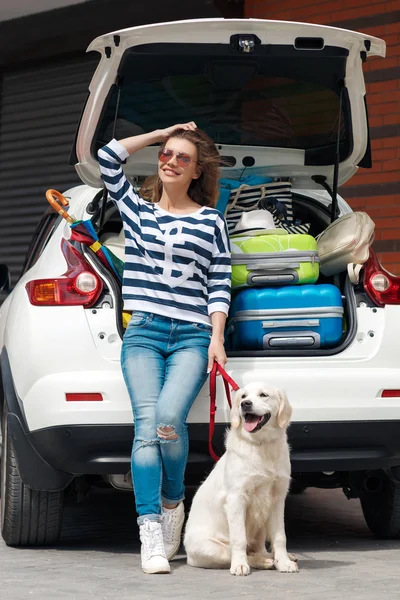 Woman with dog by car full of suitcases. — Stock Photo, Image