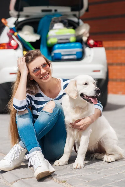 Woman with dog by car full of suitcases. — Stock Photo, Image