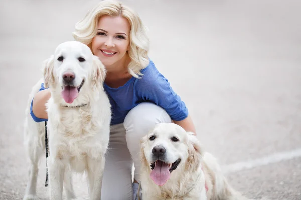 Mujer rubia con dos labradores dorados al aire libre . — Foto de Stock