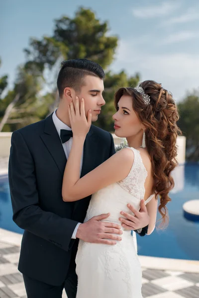 La novia y el novio junto a la piscina con agua azul —  Fotos de Stock