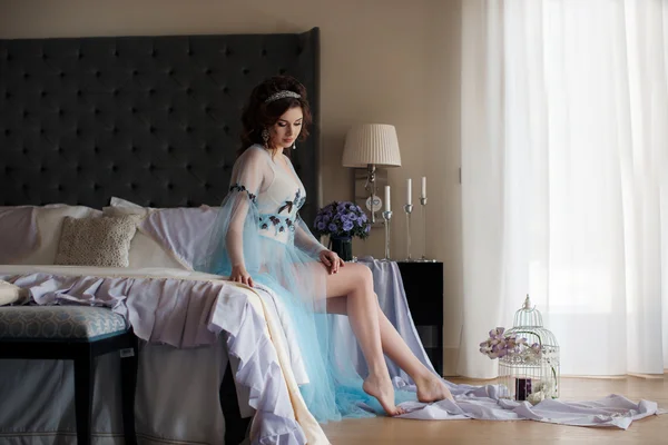 Beautiful woman sitting on a luxurious bed — Stock Photo, Image